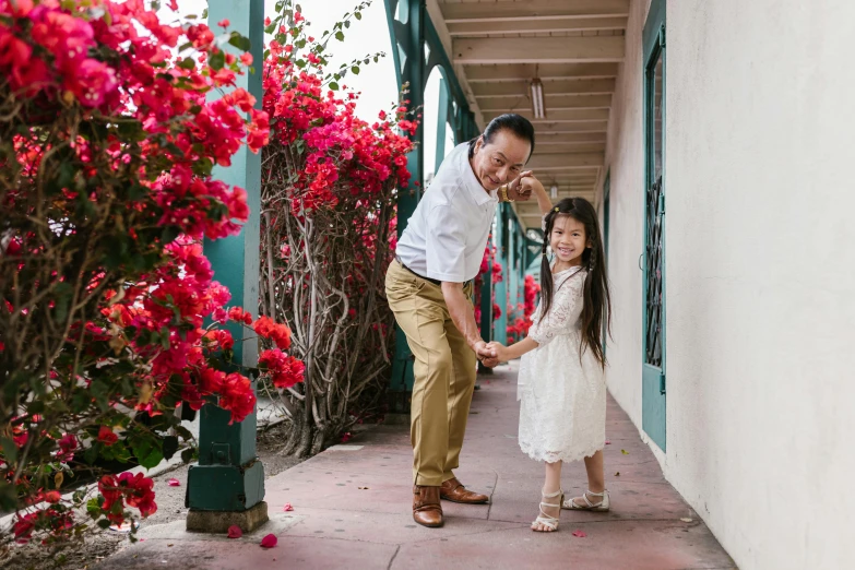 a man and a little girl holding hands, pexels contest winner, bougainvillea, avatar image, jackie tsai style, doing a sassy pose