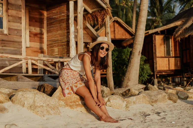 a woman sitting on a rock on the beach, by Emma Andijewska, pexels contest winner, sumatraism, stood outside a wooden cabin, avatar image, tan skin, tropical style