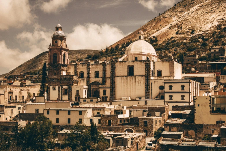 a view of a town with a mountain in the background, a colorized photo, pexels contest winner, baroque, brutalist aztec architecture, domes, white, brown