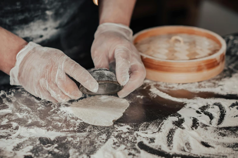 a person in white gloves making dough on a table, a silk screen, trending on unsplash, dumplings on a plate, stone carving, profile image, wearing silver silk robe