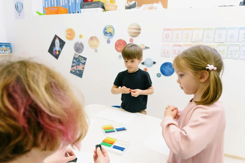 a couple of kids that are sitting at a table, a child's drawing, pexels contest winner, danube school, floating planets, whiteboards, white wall coloured workshop, lachlan bailey