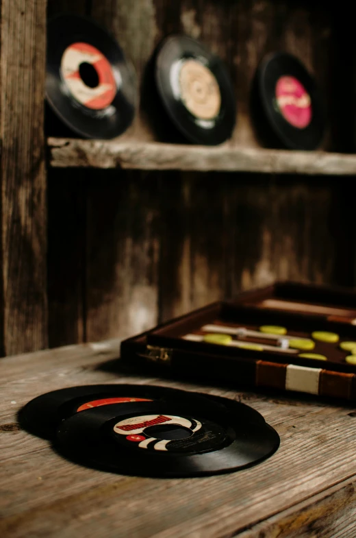 a record sitting on top of a wooden table, cigarrette boxes at the table, black vertical slatted timber, zoomed in, aged