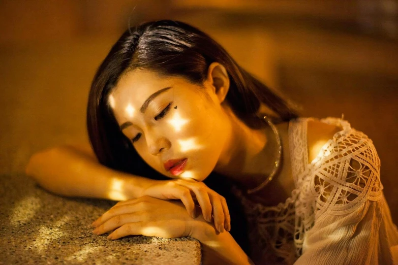 a woman leaning on a wall with her eyes closed, inspired by Elsa Bleda, pexels contest winner, hyperrealism, gold dappled light, asian woman, lie on a golden stone, soft moonlight lighting