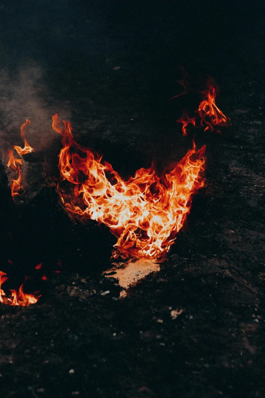 a person laying on the ground in front of a fire, pexels contest winner, fiery wings, flaming heart, grainy, destruction