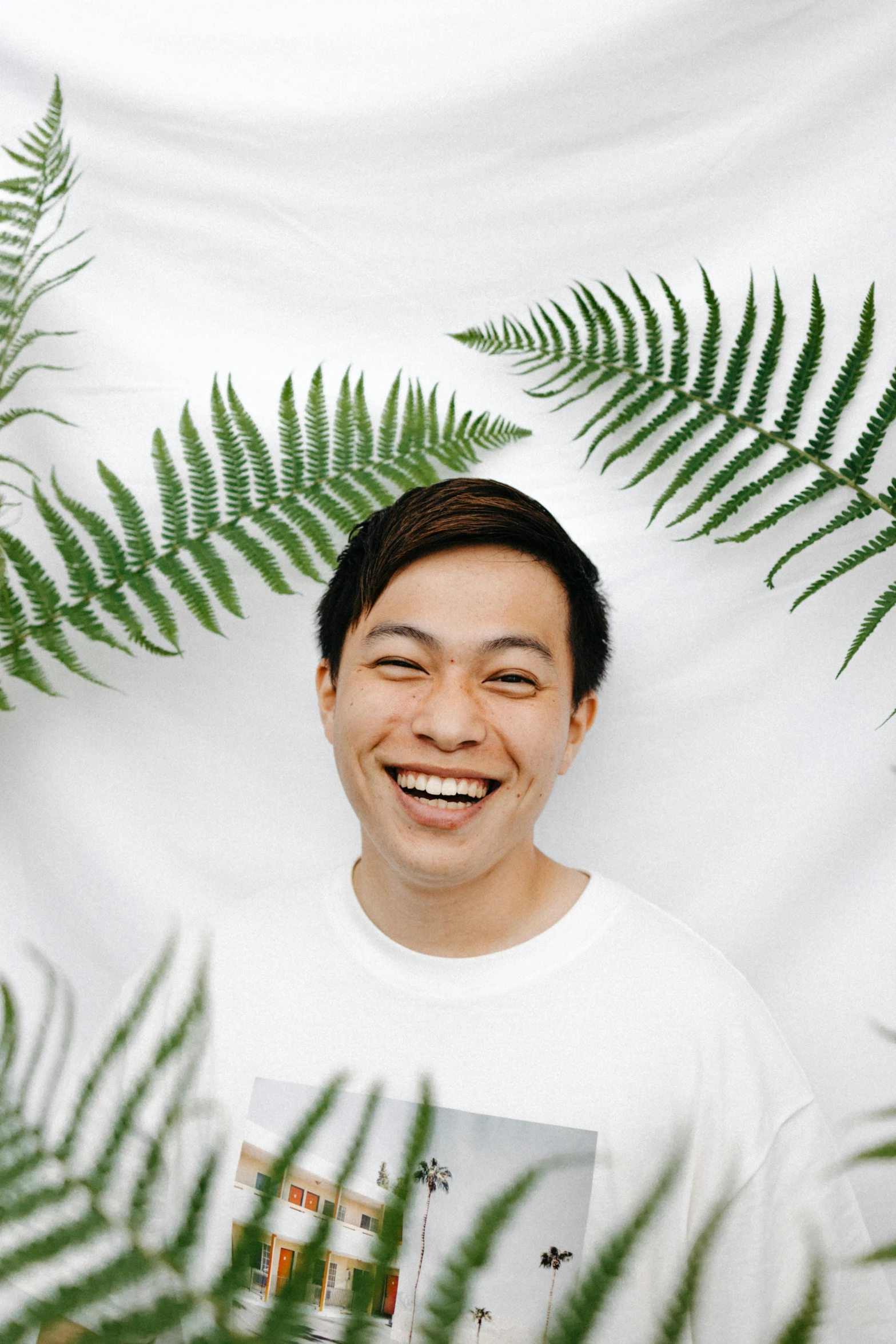 a man that is standing in front of some plants, inspired by Reuben Tam, pexels contest winner, sumatraism, smiling mouth, in front of white back drop, fern, half asian