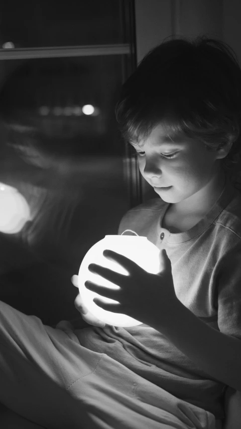 a black and white photo of a child playing with a ball, magical realism, holding glowing laptop computer, plasma globe, holding a lantern, istock