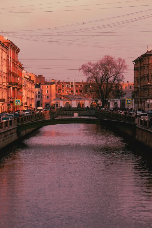 a river running through a city next to tall buildings, a picture, by Serhii Vasylkivsky, pink arches, saint petersburg, warm glow, 2022 photograph