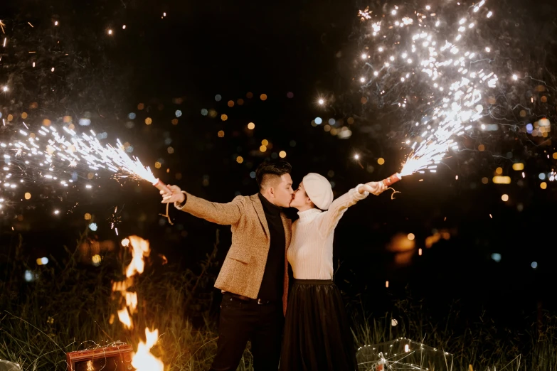 a man and a woman standing next to a fire, by Julia Pishtar, pexels contest winner, sparklers, background image, cutest, riyahd cassiem