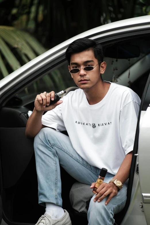 a man sitting in a car smoking a cigarette, inspired by Rudy Siswanto, pexels contest winner, white tshirt, trending on r/streetwear, long shirt, official product photo