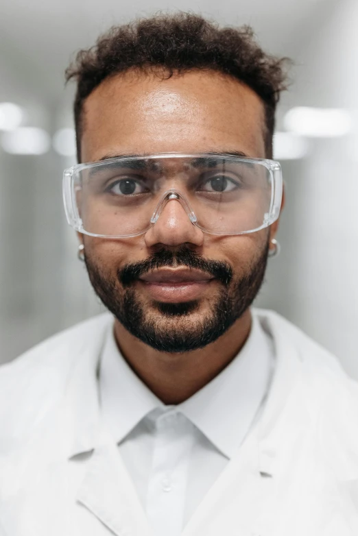 a man in a lab coat and safety glasses, pexels contest winner, square masculine facial features, riyahd cassiem, androgynous person, short beard