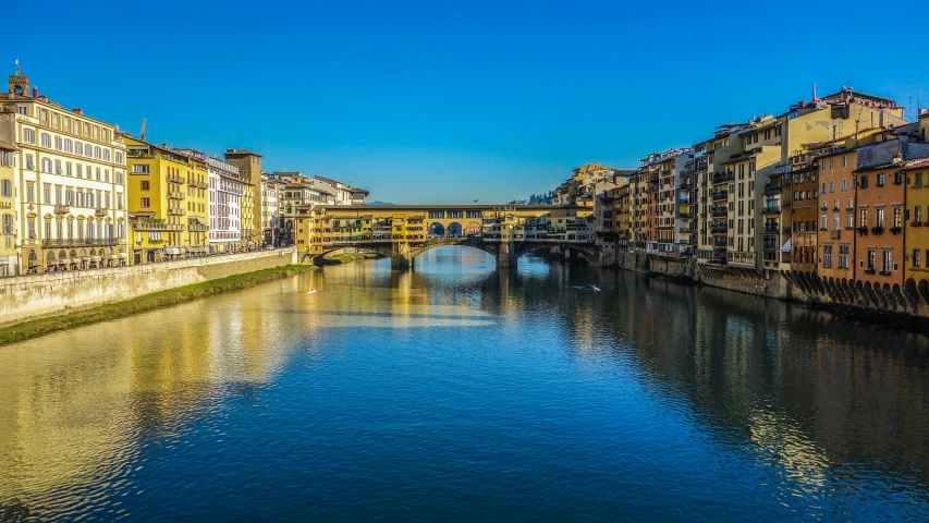 a river running through a city next to tall buildings, by Carlo Martini, pexels contest winner, renaissance, blue and gold, florence, sunny light, bridge over the water