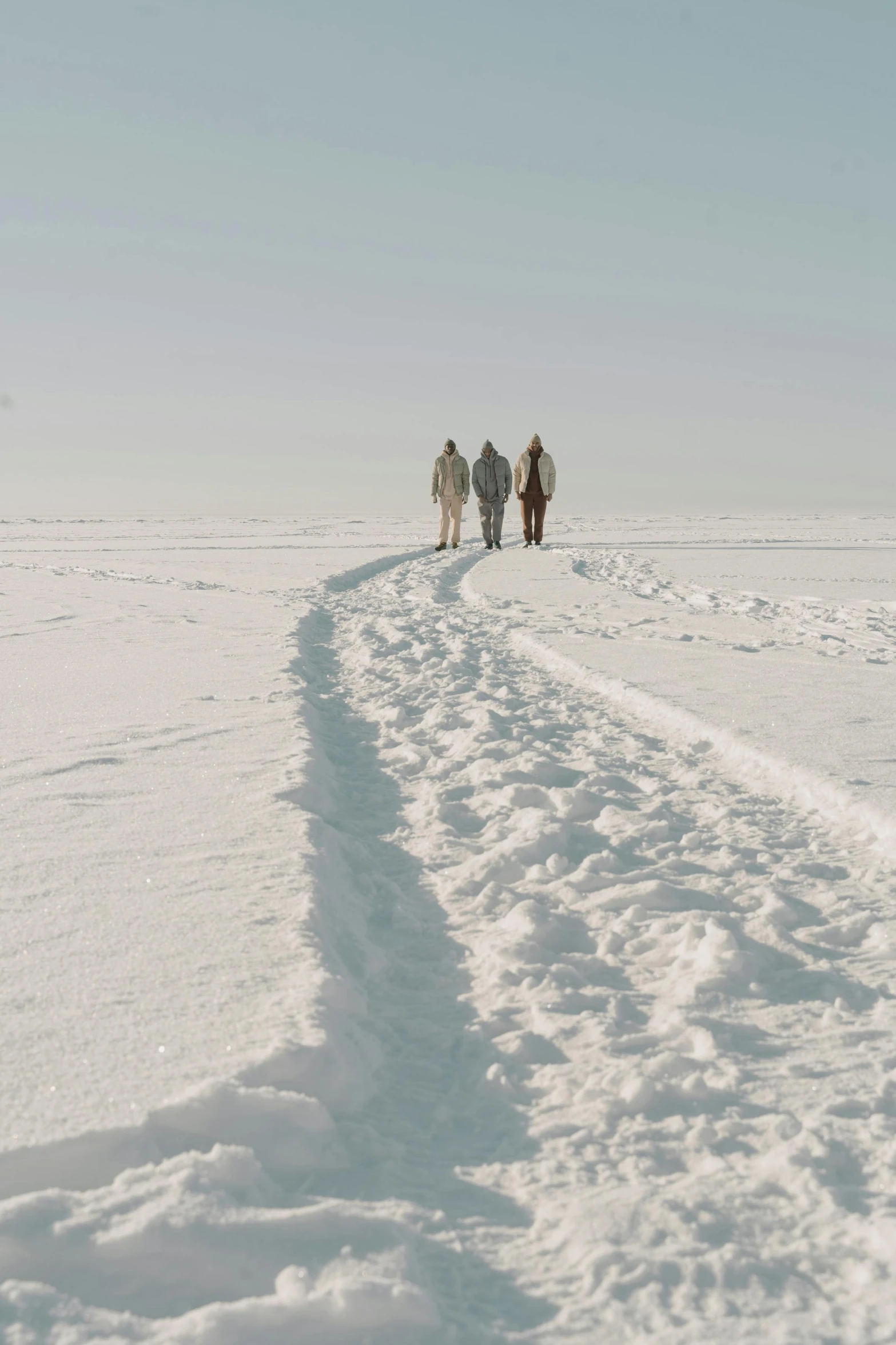 a group of people walking across a snow covered field, inspired by Einar Hakonarson, trending on unsplash, land art, white beaches, ignant, ultrawide cinematic, (3 are winter