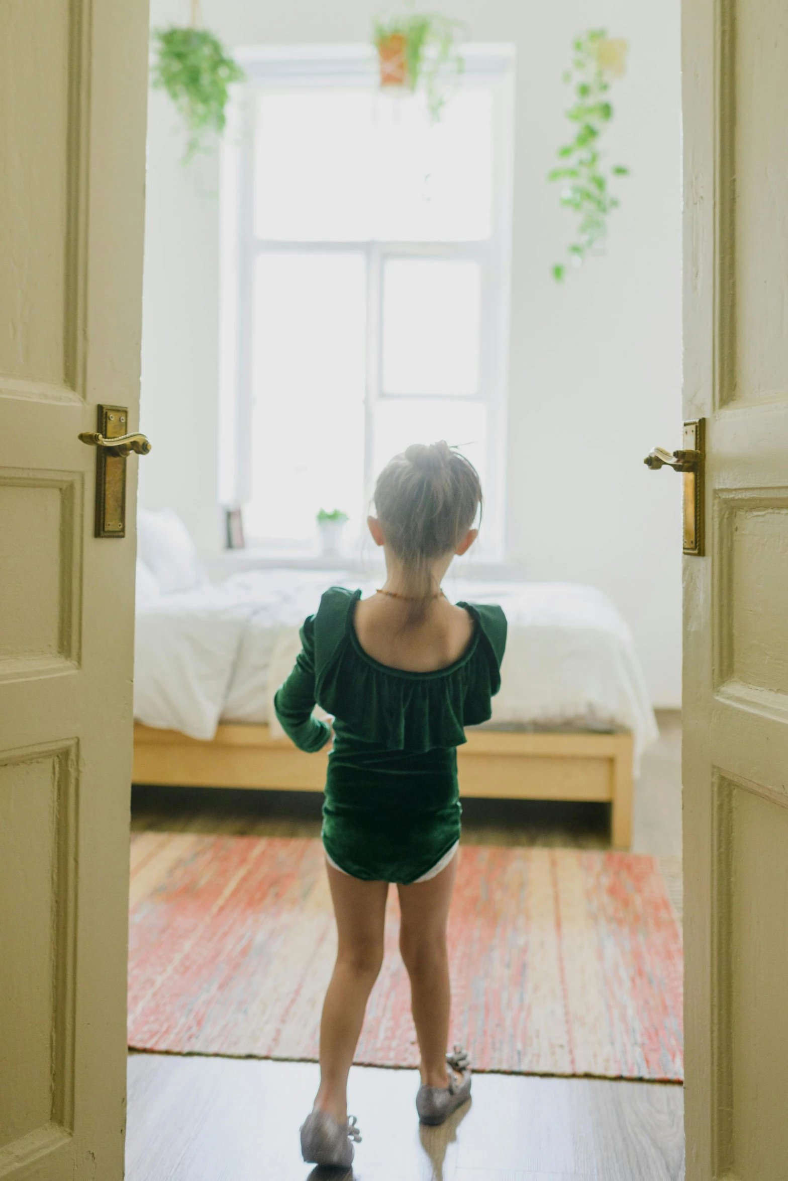 a little girl standing in front of an open door, pexels contest winner, wearing leotard, deep green, bedroom, ignant