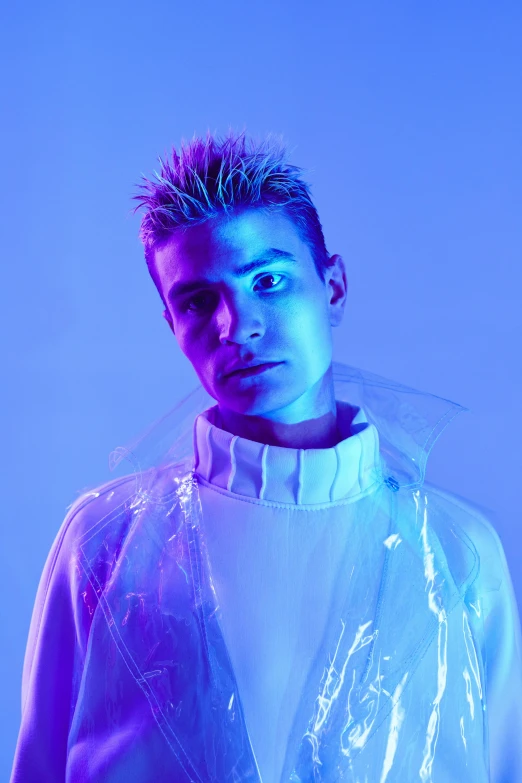 a man standing in front of a blue background, an album cover, inspired by Adrian Zingg, justin bieber, cybernetic glowing, looking away from camera, an all white human