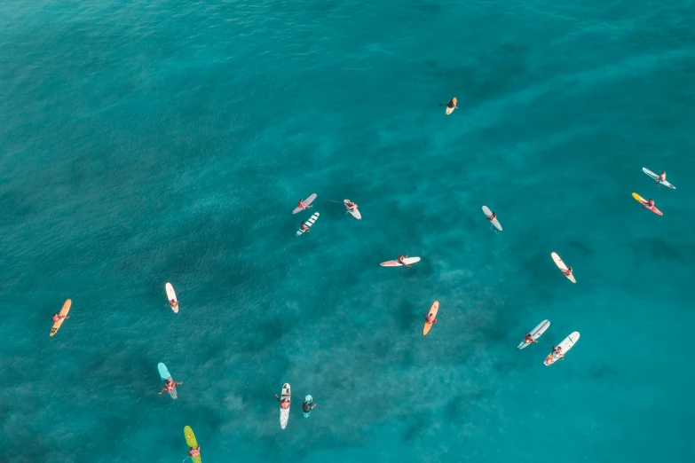 a group of people riding surfboards on top of a body of water, by Emma Andijewska, pexels contest winner, turquoise, small canoes, taken from a plane, thumbnail