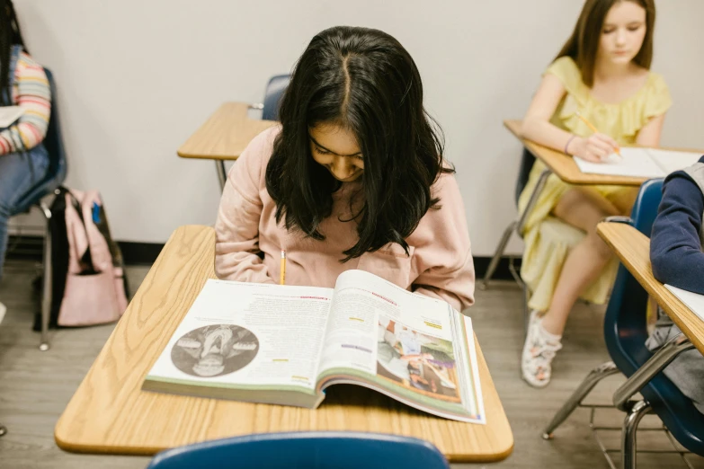 a group of children sitting at desks in a classroom, pexels contest winner, hyperrealism, village girl reading a book, kailee mandel, a young asian woman, 15081959 21121991 01012000 4k