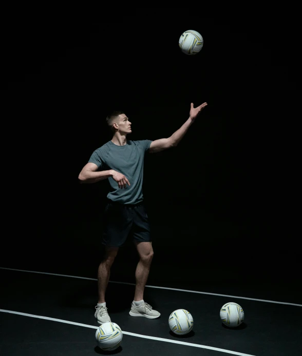 a man standing on top of a tennis court holding a racquet, a portrait, by Carey Morris, pexels, conceptual art, flying soccer balls, in front of a black background, soccer player martin ødegaard, wearing a volleyball jersey