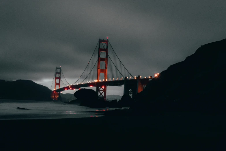 the golden gate bridge is lit up at night, pexels contest winner, surrealism, grey and dark theme, overcast, dark building, instagram post