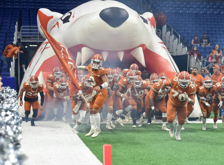 a group of football players running on a field, giant kaiju starfish monster, orange fur, inside the tunnel, alabama