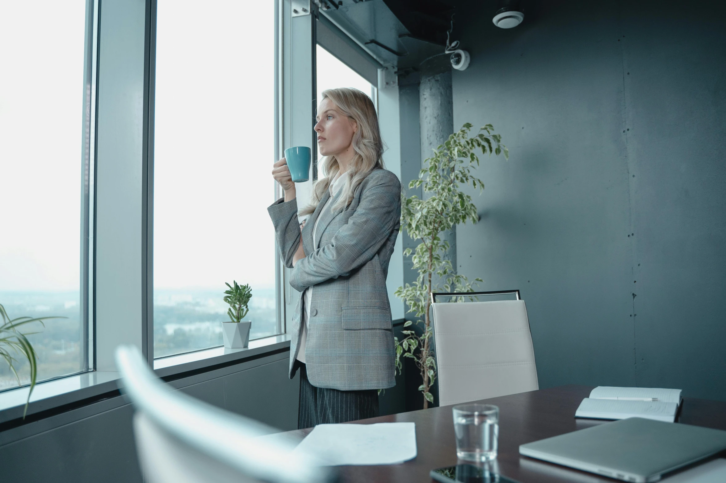 a woman standing in front of a window holding a cup, pexels contest winner, in a meeting room, avatar image, trending photo, looking to the sky