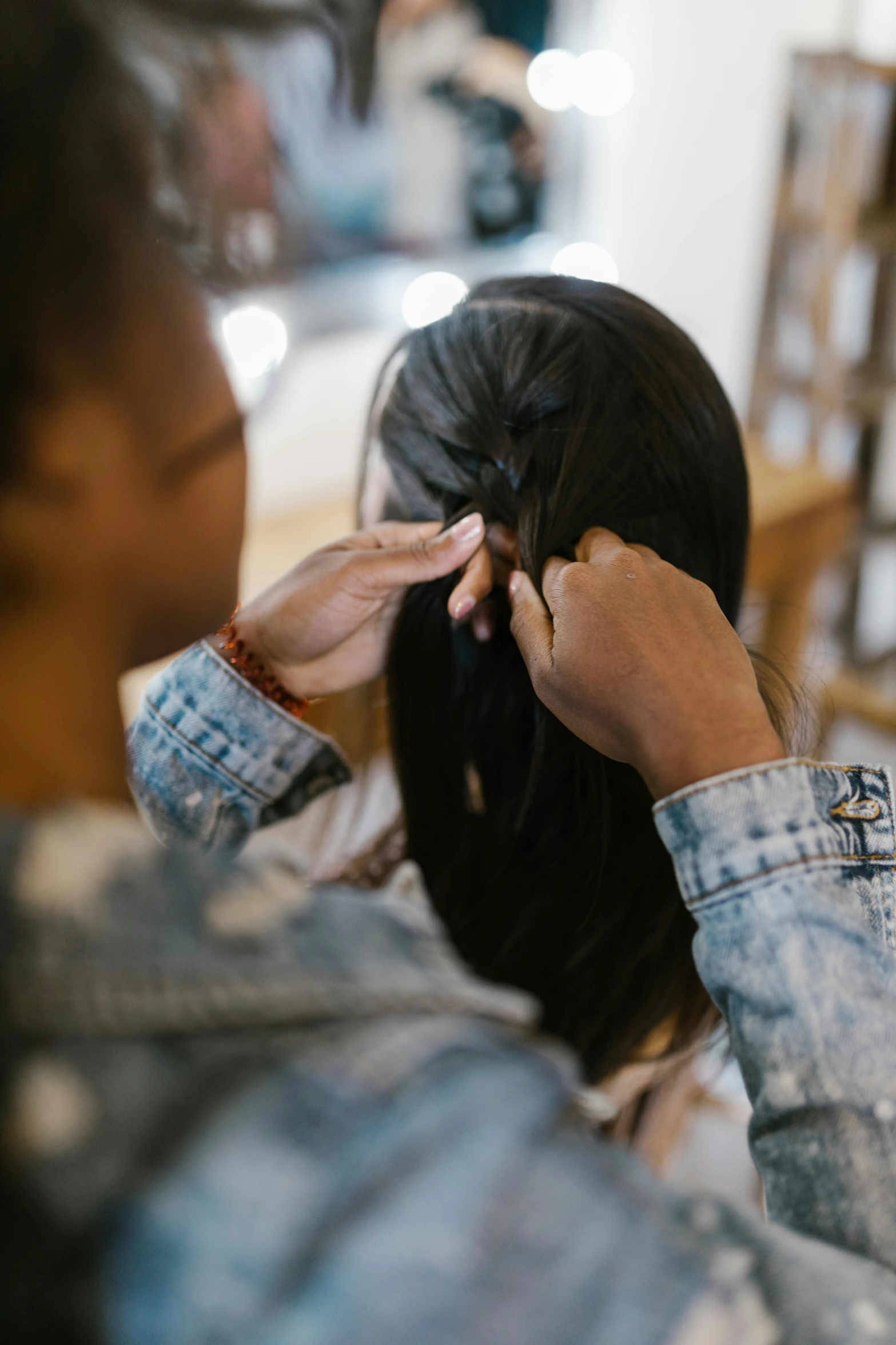 a woman cutting another woman's hair in a salon, trending on pexels, renaissance, long black braided hair, hands reaching for her, instruction, backfacing