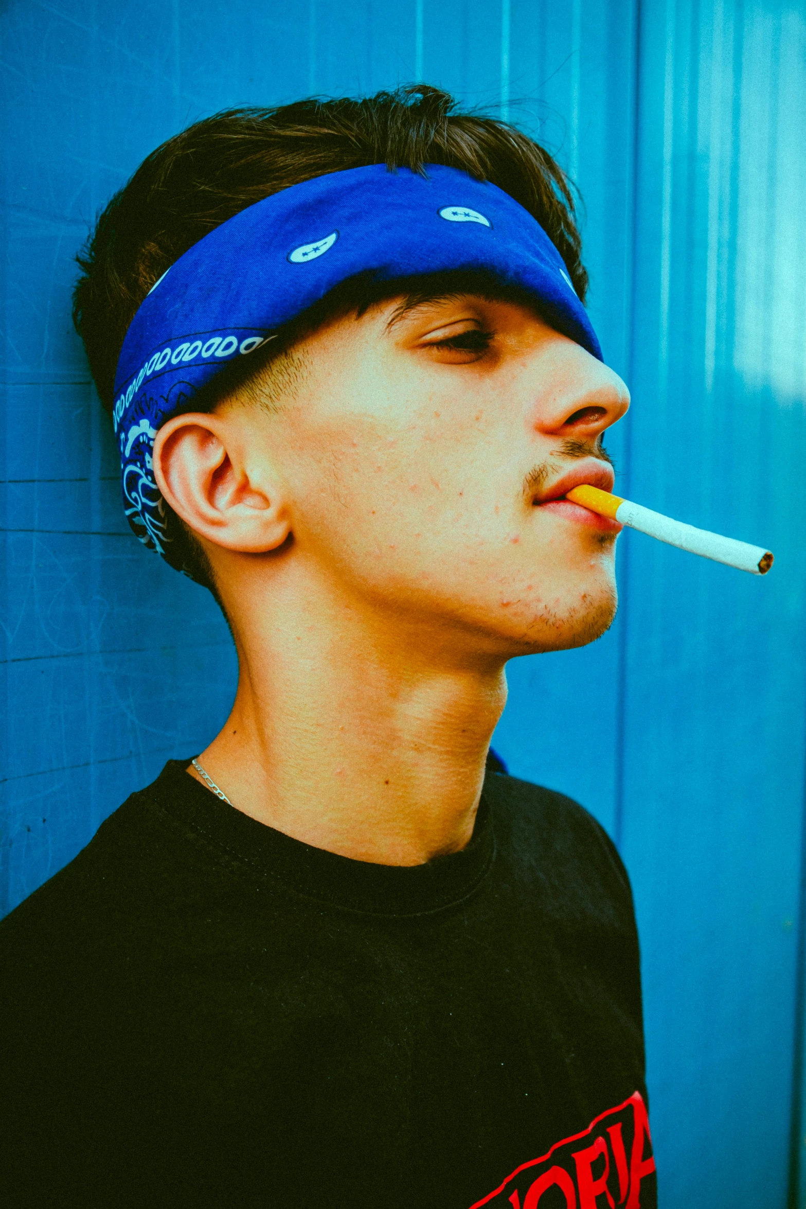 a man with a cigarette in his mouth, an album cover, inspired by Jean Malouel, trending on pexels, wearing the number 1 headband, ((blue)), teen boy, enes dirig