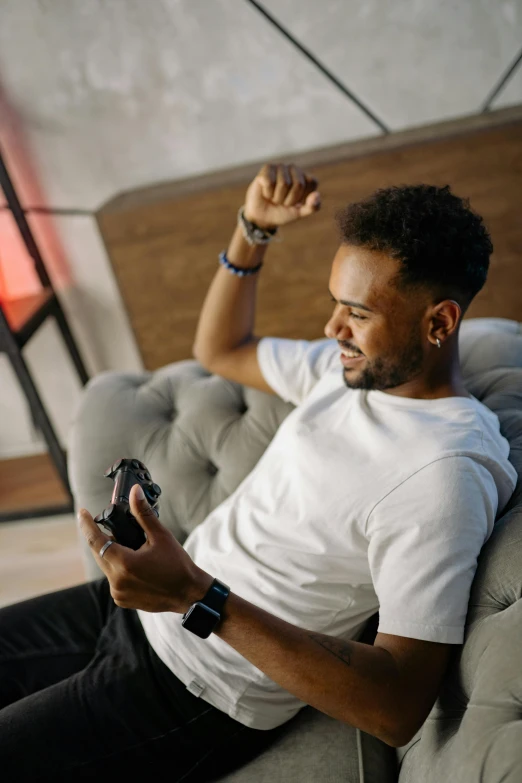 a man sitting on a couch playing a video game, pexels contest winner, black man, lean man with light tan skin, showing victory, samsung smartthings