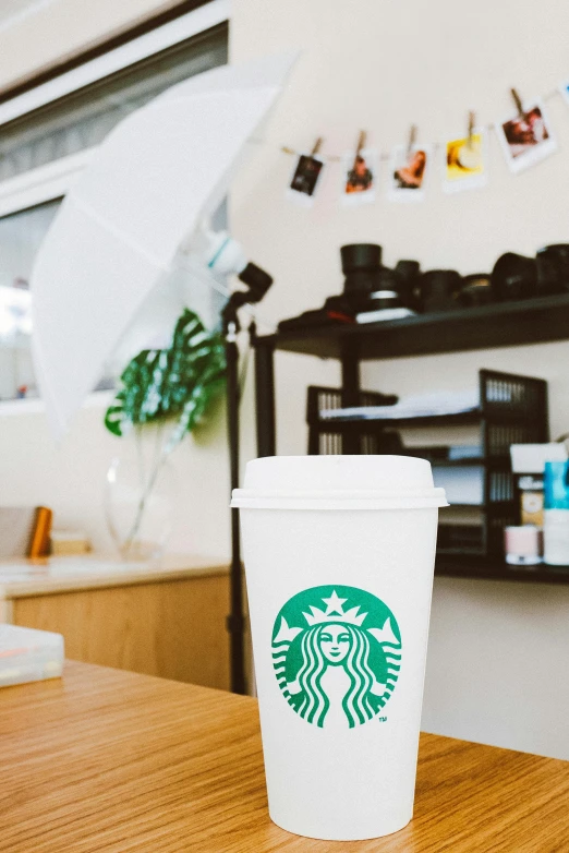 a starbucks cup sitting on top of a wooden table, a polaroid photo, backrooms office space, products shot, multiple stories, jar on a shelf