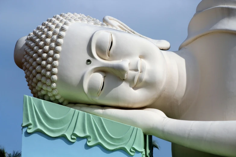 a close up of a statue of a person laying down, the buddha, on a bright day, puṣkaracūḍa, simon lee