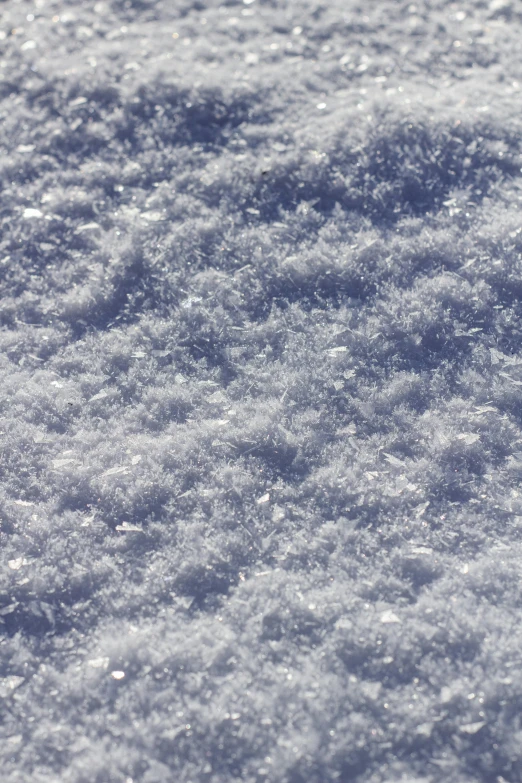 a pile of snow sitting on top of a snow covered ground, zoomed in shots, surface blemishes, platinum, slightly sunny weather