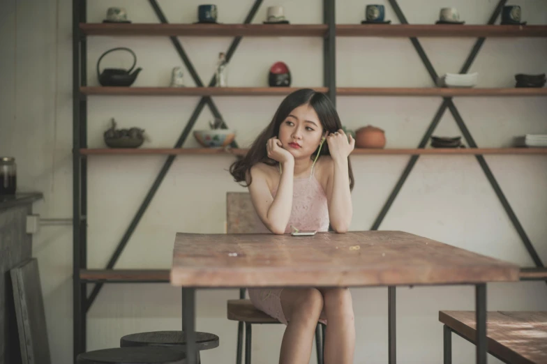 a woman sitting at a table in a kitchen, by Jang Seung-eop, pexels contest winner, full body cute young lady, sitting on a mocha-colored table, sad feeling, sitting on a store shelf