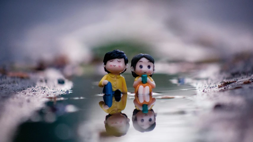 a couple of figurines sitting on top of a puddle of water, a tilt shift photo, inspired by Nara Yoshitomo, unsplash, 5 0 0 px, plastic toy, low angle photo