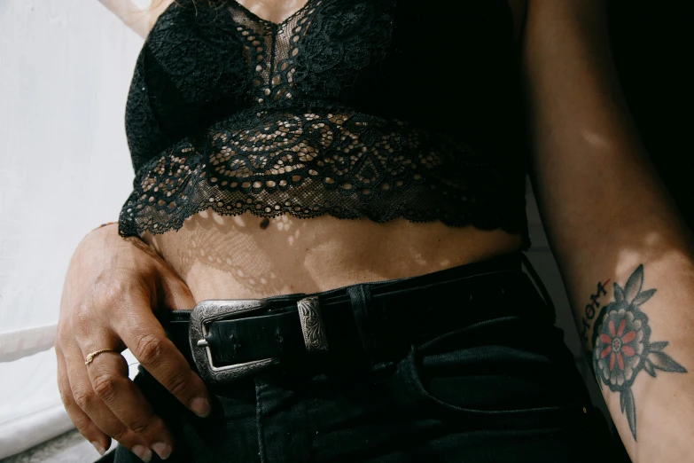 a close up of a person with a tattoo on their arm, inspired by Elsa Bleda, trending on pexels, renaissance, leather pants with a belt, physical : tinyest midriff ever, dressed in black lace, bralette