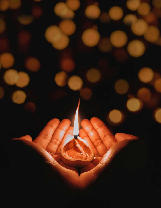 a person holding a lit candle in their hands, by Julia Pishtar, pexels contest winner, background image, multiple stories, lgbtq, holding a holy symbol