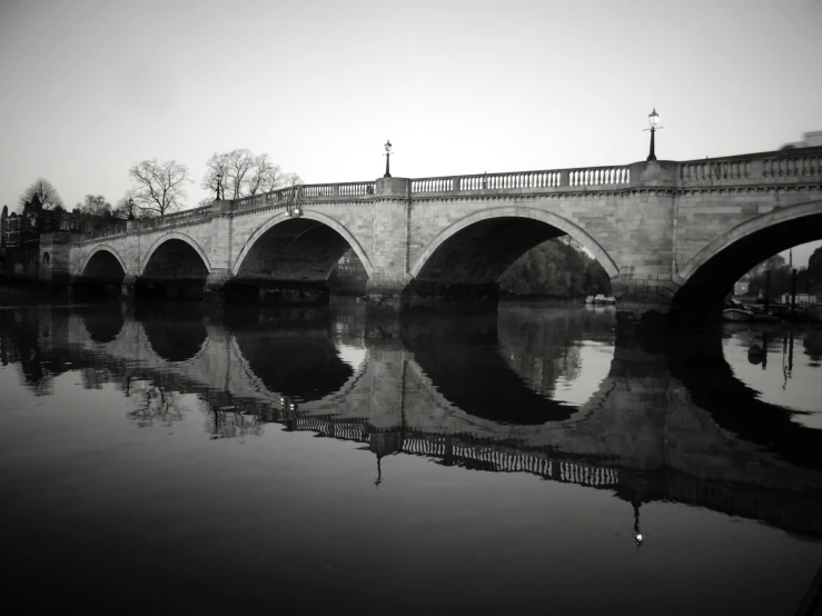 a black and white photo of a bridge over water, a black and white photo, inspired by Richmond Barthé, pexels contest winner, reflective scales, regency-era, white sweeping arches, detailed medium format photo