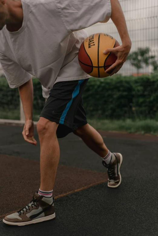 a man standing on a basketball court holding a basketball, trending on dribble, wearing shorts, gray shorts and black socks, tapping in to something greater, wearing golf shorts