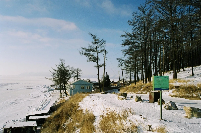 a green sign sitting on the side of a snow covered slope, hurufiyya, near the seashore, soviet town, exterior photo, blue