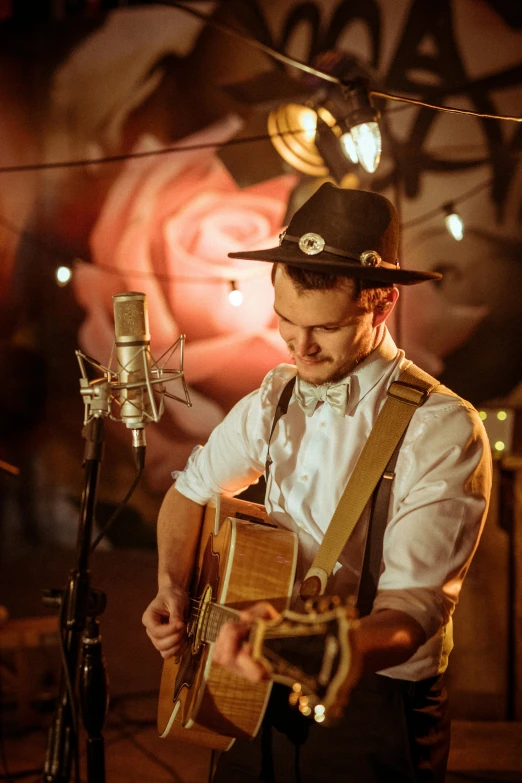 a man playing a guitar in front of a microphone, an album cover, pexels contest winner, 1 9 2 0's style speakeasy, melanchonic rose soft light, high quality photo, wearing a straw hat and overalls