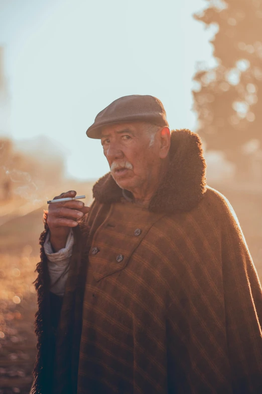 a man standing on a train track smoking a cigarette, a portrait, by Adam Marczyński, pexels contest winner, two aboriginal elders, with a cup of hot chocolate, wearing hay coat, golden hour cinematic