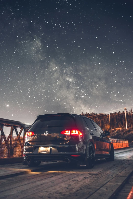 a car driving across a bridge at night, unsplash contest winner, romanticism, stars and planets, wrx golf, cars parked underneath, back