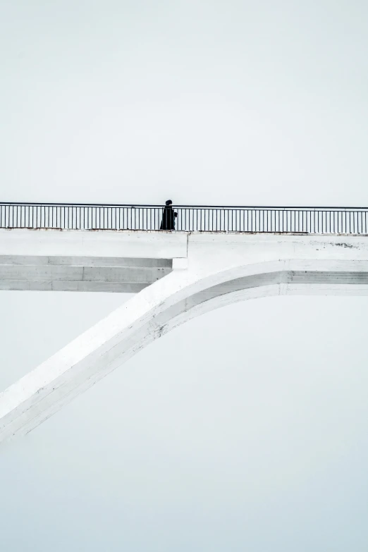 a person walking across a bridge in the snow, a minimalist painting, by Joze Ciuha, postminimalism, white concrete, pondering, unsplash photography, thinker