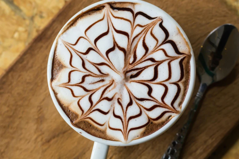 a close up of a cup of coffee on a table, arabesque, fully chocolate, thumbnail, artisanal art, latte art