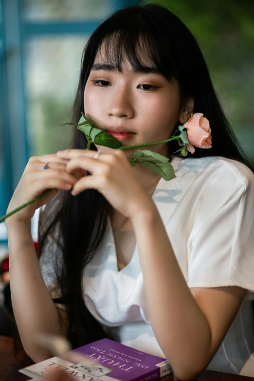 a woman sitting at a table with a rose in her hand, by Tan Ting-pho, trending on pexels, young adorable korean face, modeled, close up half body shot, lily