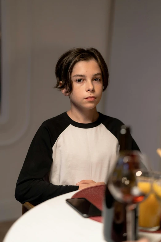 a young boy sitting at a table with a bottle of beer, trending on reddit, in a scifi movie, high-quality photo, boyish face, lachlan bailey