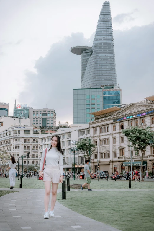 a woman in a white dress walking down a sidewalk, an album cover, inspired by Ruth Jên, trending on unsplash, tall buildings in background, vietnam, 🚿🗝📝, panoramic view of girl