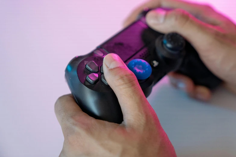 a close up of a person holding a video game controller, magenta and blue, shot on sony a 7, tabletop gaming, playstation 4