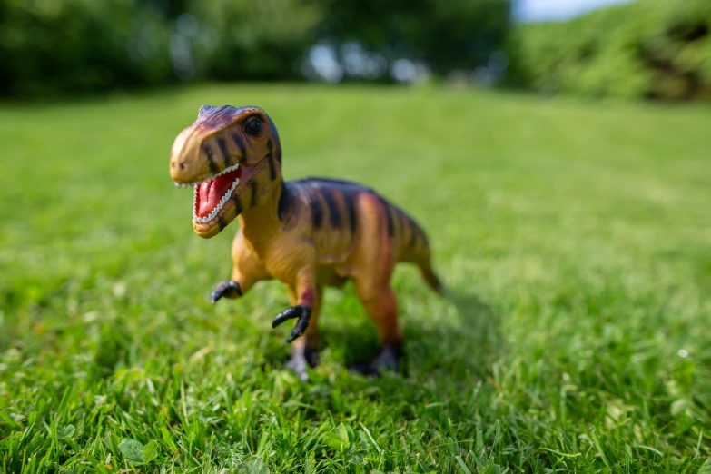 a toy dinosaur standing on top of a lush green field, unsplash, photorealism, roaring, pvc poseable, hand, 🦑 design