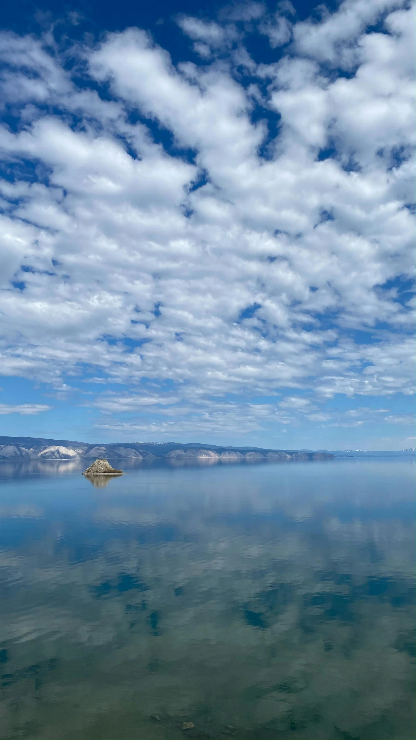 a large body of water with some clouds in the sky, by Jim Nelson, unsplash contest winner, wyoming, calm sea, crater lake, 2022 photograph