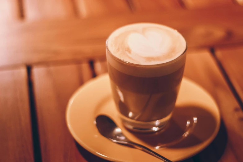 a cup of coffee sitting on top of a saucer, on a wooden table, aussie baristas, profile image, vanilla