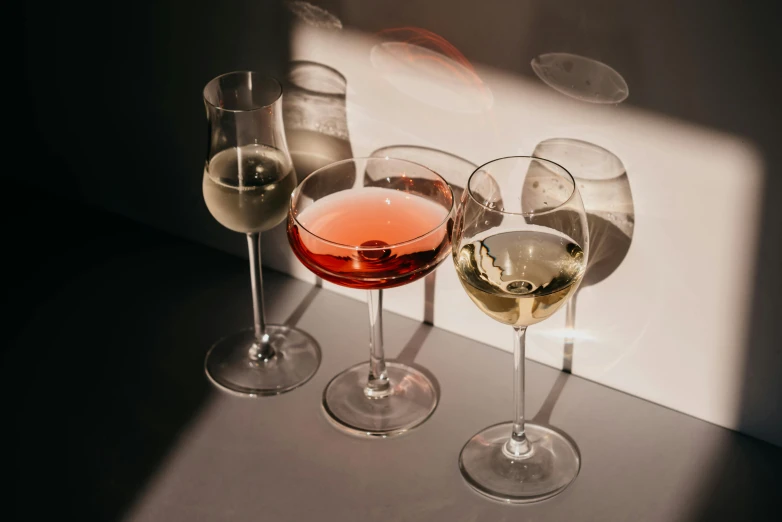 three wine glasses sitting next to each other on a table, pexels contest winner, various posed, minimalist, with a drink, mead